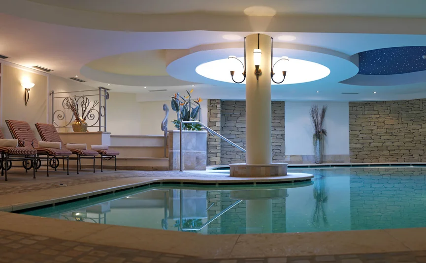 Indoor pool with lounge chairs and decorative stone wall