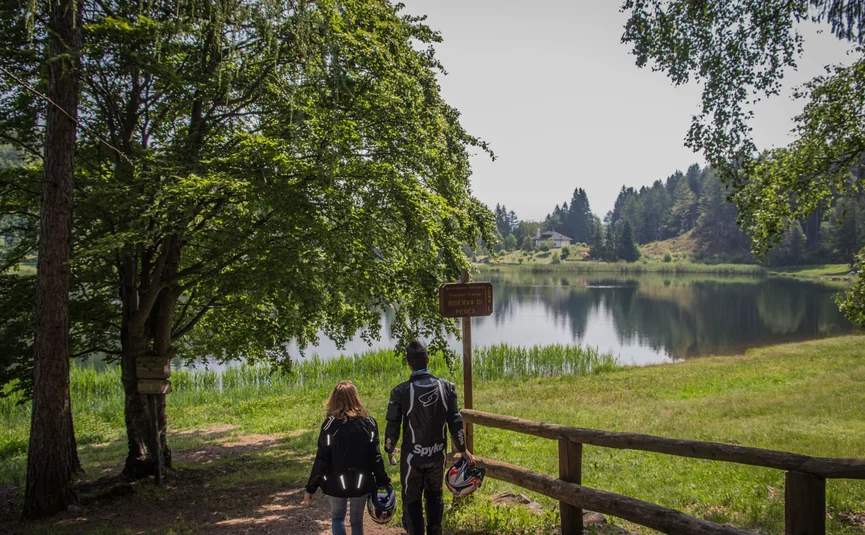 Hotel La Stüa **** © A. Monticelli Zwei Menschen gehen mit Motorradhelmen am See entlang in grüner Landschaft