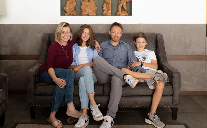 Family with mother, father, daughter, and son sitting on couch smiling