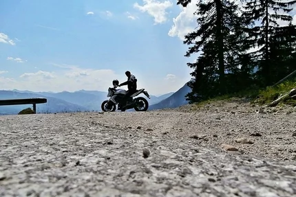Motorcyclist on mountain road with mountains and trees in background
