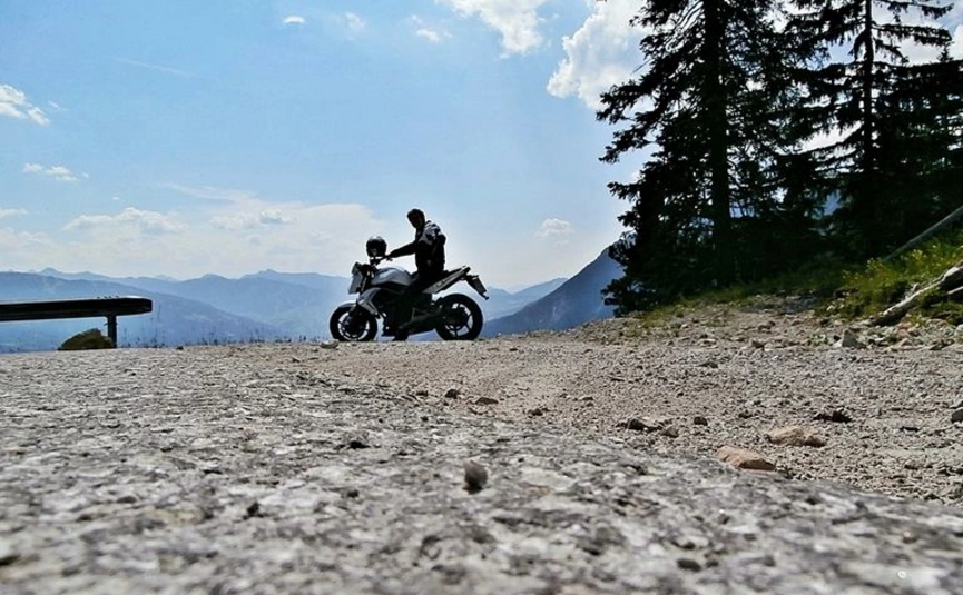 Motorradfahrer auf Bergstraße mit Bergen und Bäumen im Hintergrund