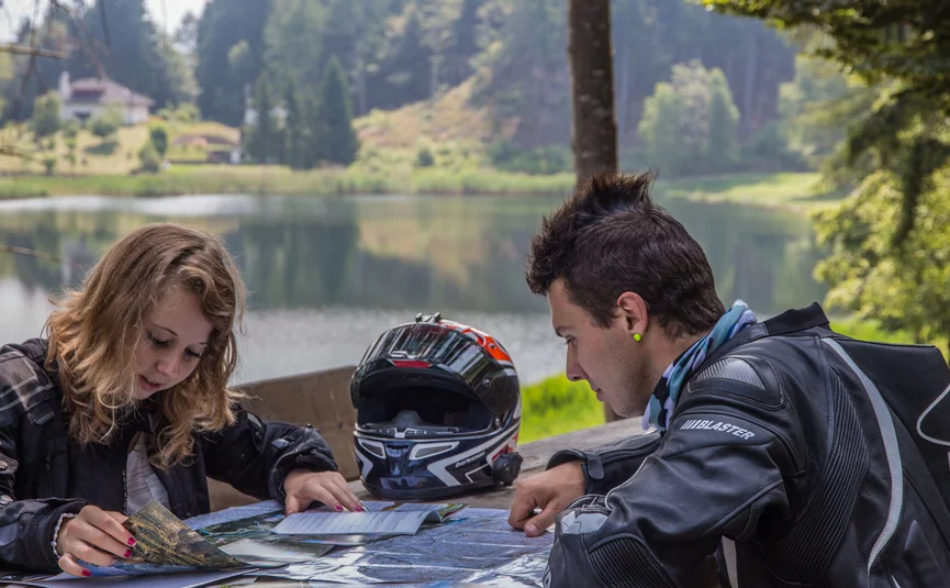 Hotel La Stüa **** © A. Monticelli Zwei Motorradfahrer planen ihre Route mit Landkarten an einem See