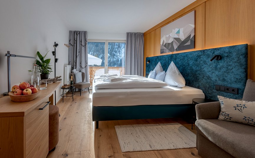 Moderne hotelkamer met groot bed, houten wandpaneel en berguitzicht