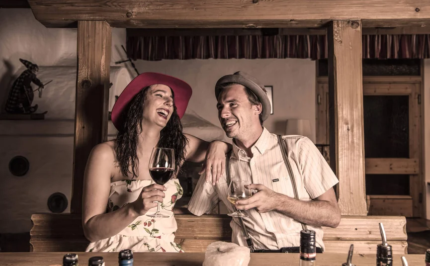 Couple laughing and drinking wine in rustic wooden bar