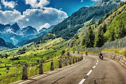 Motorrijders op kronkelige bergweg met Alpenlandschap