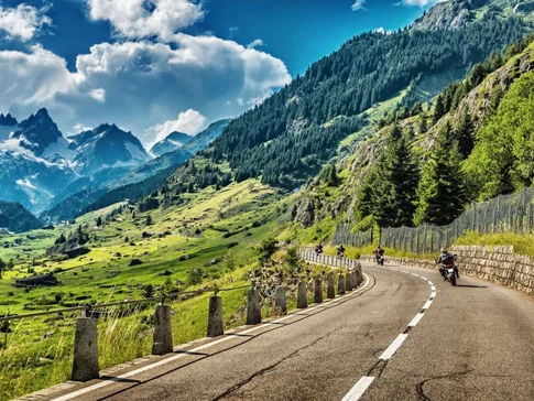 Motorradfahrer auf kurviger Bergstraße mit Alpenpanorama
