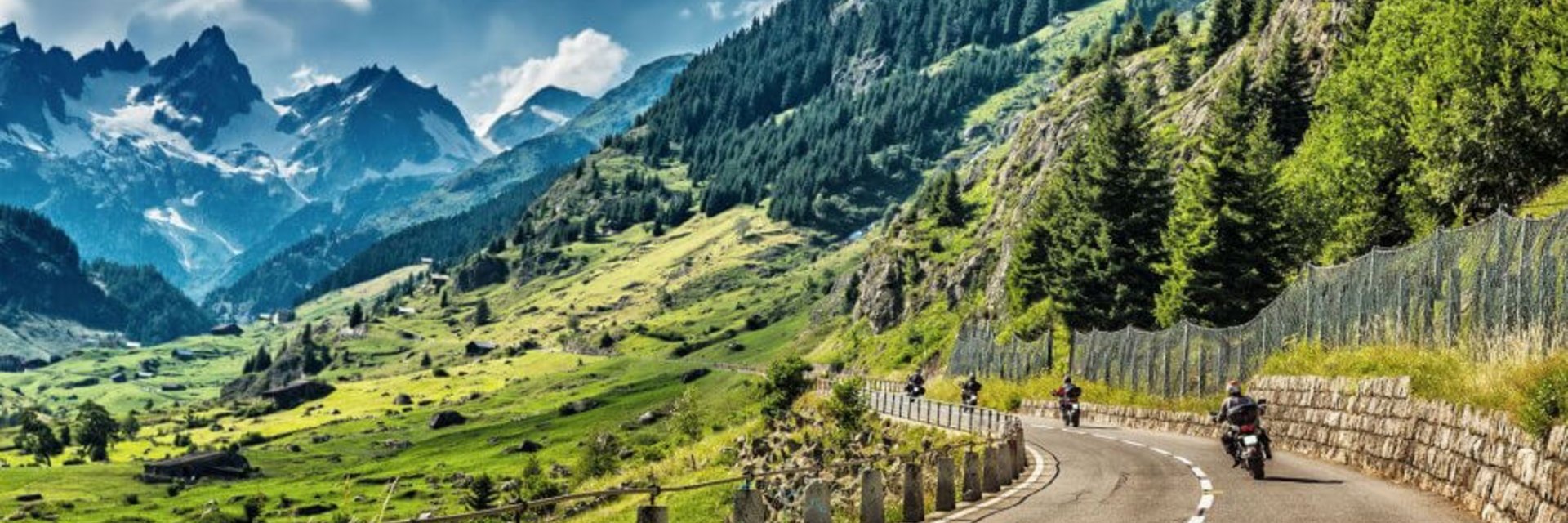Motorradfahrer auf kurviger Bergstraße mit Alpenpanorama