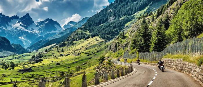 Motorrijders op kronkelige bergweg met Alpenlandschap