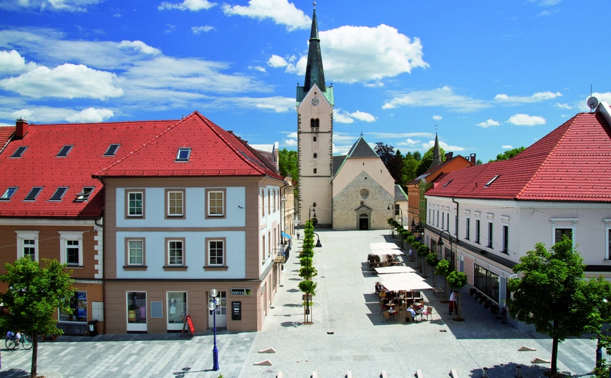 Erfgoedrit Karinthië Stadsplein met kerk en rode daken onder blauwe lucht