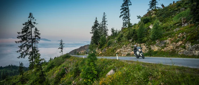 Motorradfahrer auf Bergstraße mit Blick auf Nebel und Bäume