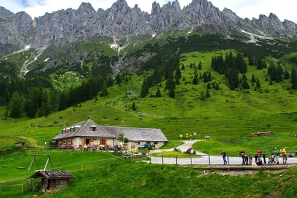 Berglandschaft mit grünem Tal und Hütte unter felsigen Gipfeln
