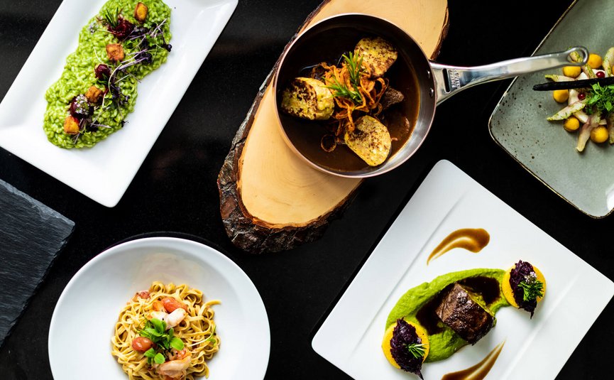 Motorrad- & Spa Hotel Traube Post am Reschensee **** © Theiner Karl-Heinz & Co KG Verschiedene kunstvoll angerichtete Gourmetgerichte auf dunklem Tisch