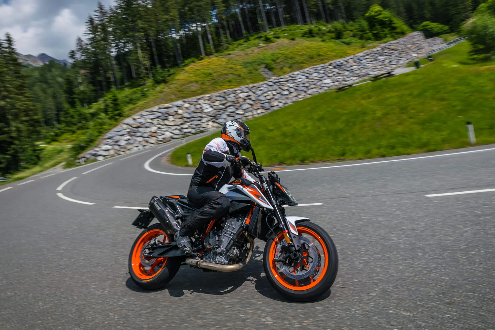 Motorradurlaub © Moppetfoto.de Motorradfahrer fährt kurvige Bergstraße mit grünem Wald im Hintergrund