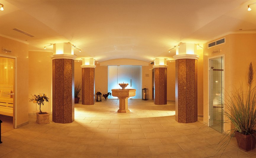 Warmer Spa-Flur mit Säulen, Pflanzen und zentralem Brunnen