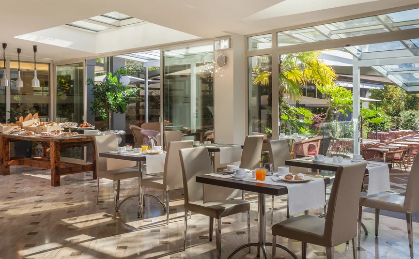 Heller Frühstücksraum mit gedeckten Tischen und Buffet