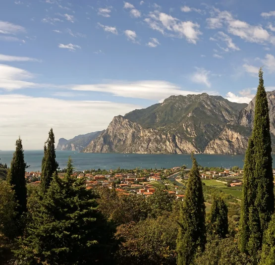 Gardasee - Short Trip Blick auf einen See mit Bergen und Zypressen im Vordergrund