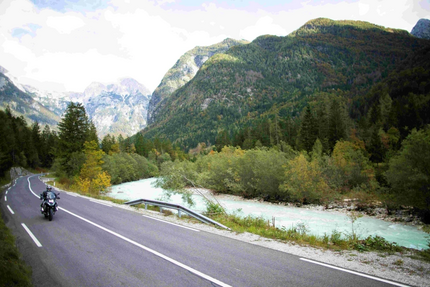Emerald Soča River & Alpine Peaks Tour Motorradfahrer auf kurvenreicher Straße neben Fluss und Bergen