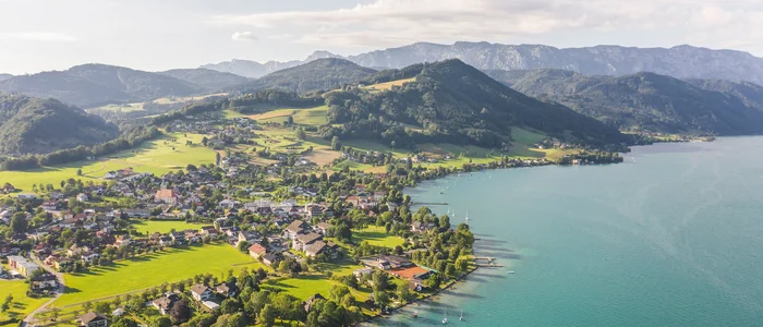 Aerial view of a lake with village and mountains in the background