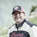 Lächelnder Mann mit Motorrad in Berglandschaft