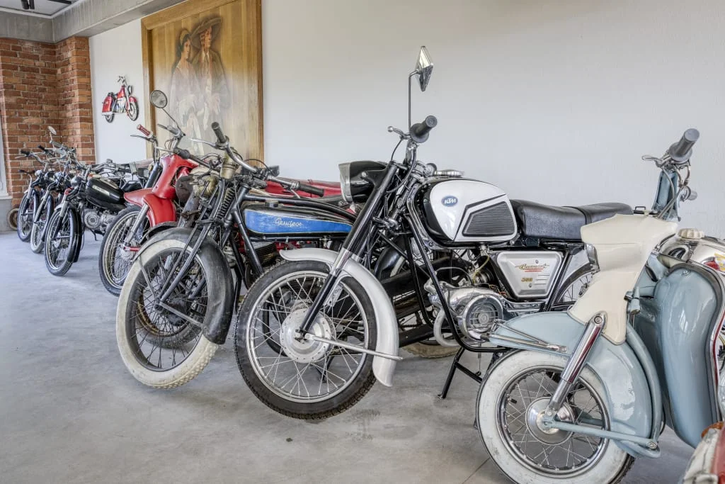 Rij klassieke motoren in kamer met bakstenen muur en kunstwerk