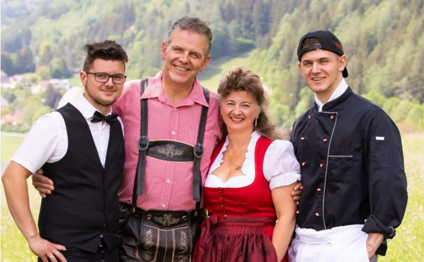 Four people smiling in traditional and professional attire outdoors