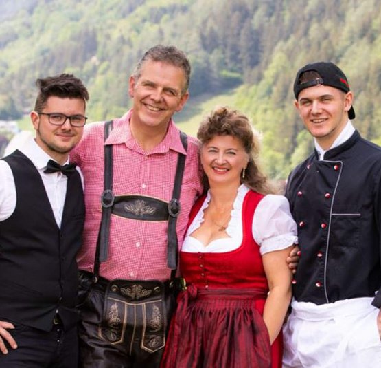 Vier Personen lächeln in traditioneller und beruflicher Kleidung im Freien