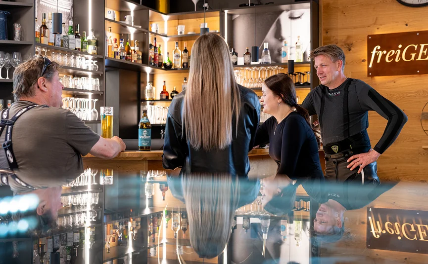 Menschen unterhalten sich an einer Bar mit Getränken und Holzinterieur
