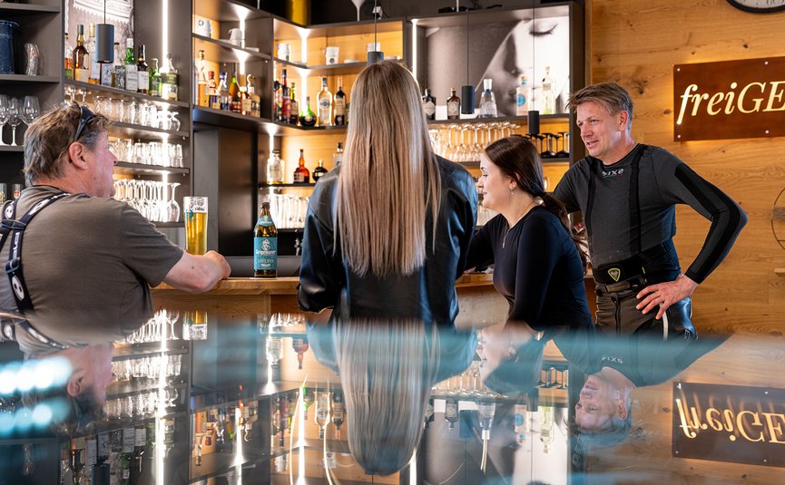 Mensen praten bij een bar met drankjes en houten interieur