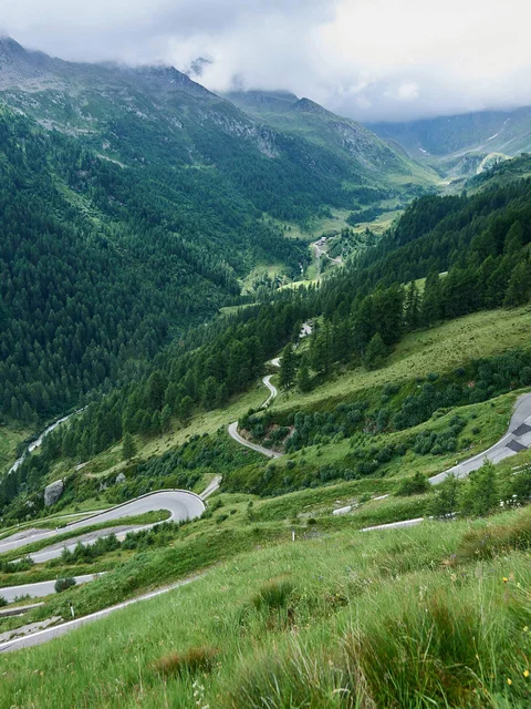 Winding mountain road in green Alps with motorcyclists