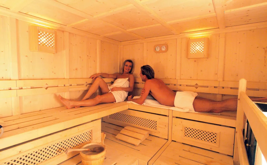 Couple relaxing inside a light wood sauna