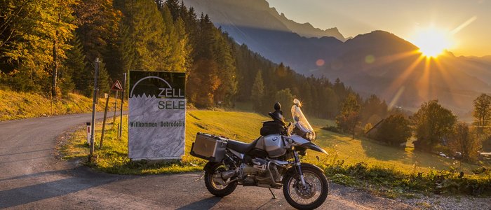 Motor op bergweg bij zonsondergang met welkomstbord