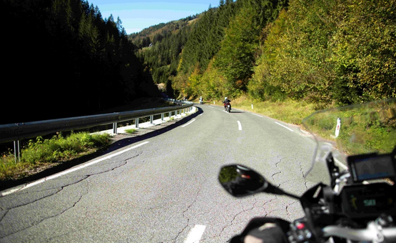Erfgoedrit Karinthië Zicht vanuit motorfietsrijder op kronkelende weg door beboste bergen