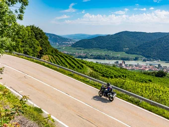 Waldviertel © Alexander Seger Motorcyclist riding on winding country road with vineyards and river view