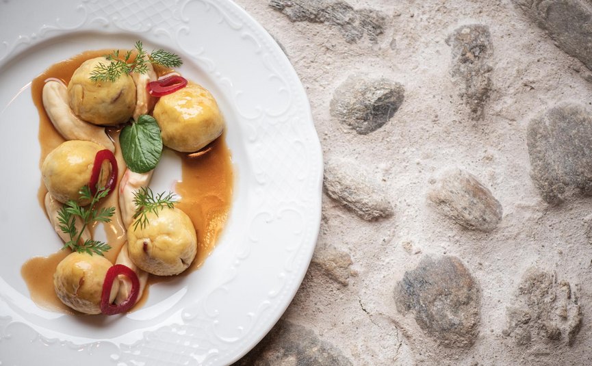 Fünf gefüllte Klöße mit Soße und Garnitur auf weißem Teller