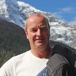 Motorradurlaub in Bayern © Hotel Bergblick Mann hält Motorradhelm und Jacke vor verschneiten Bergen