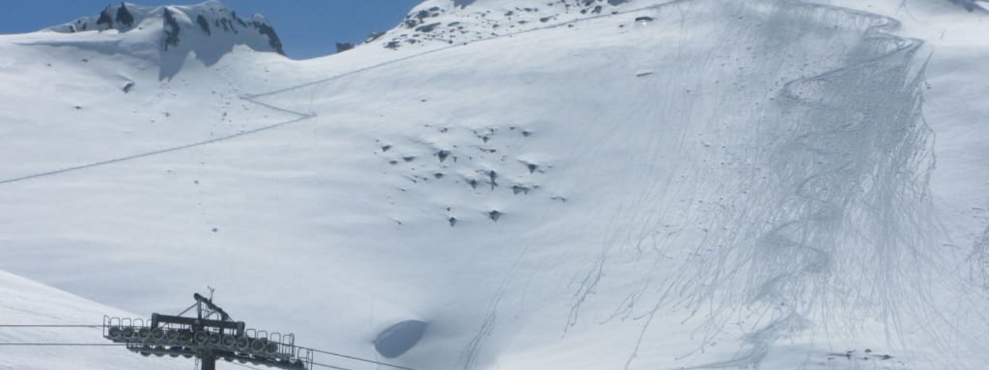 Schneebedeckter Berg mit Skilift und Ski-Spuren im Schnee