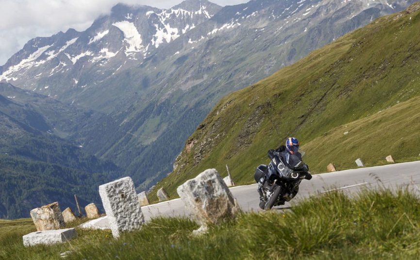 Sternfahrt Motorrad-Special ab € 628,- pro Person Motorradfahrer auf kurviger Bergstraße mit schneebedeckten Gipfeln im Hintergrund