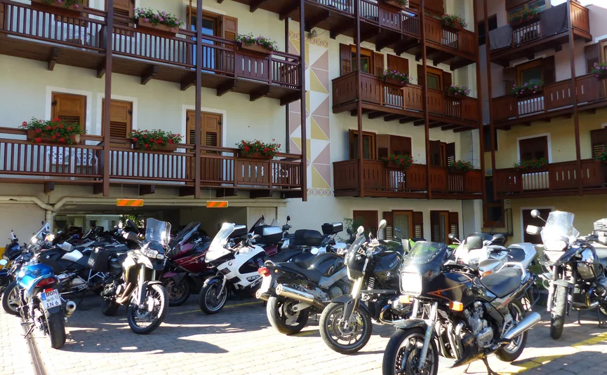 Multiple motorcycles parked in front of a building with balconies and flowers