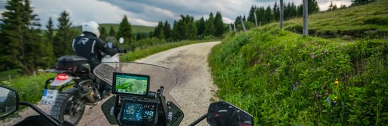 Motorradurlaub in Kärnten © Moppetfoto.de Motorradfahrer auf einem kurvigen Schotterweg in bergiger Landschaft bei bewölktem Himmel