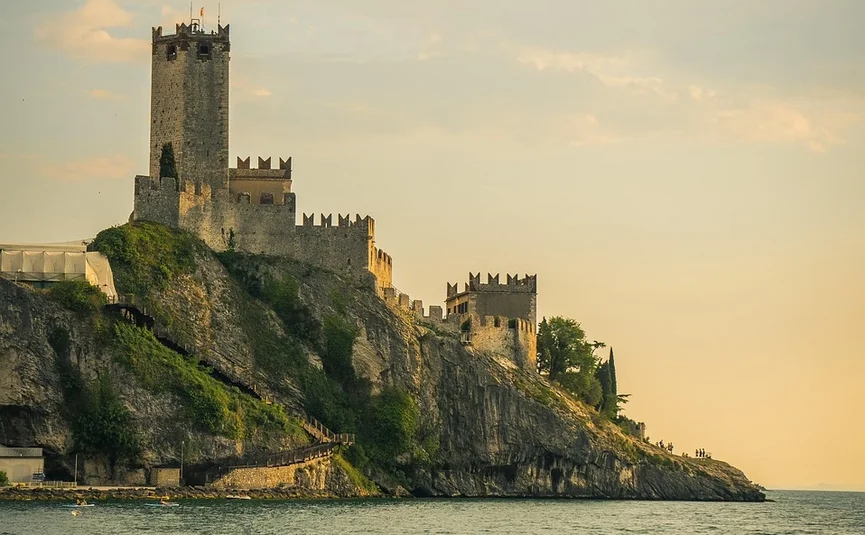 Gardasee - Short Trip Burg auf felsiger Klippe am Meer im Sonnenuntergang