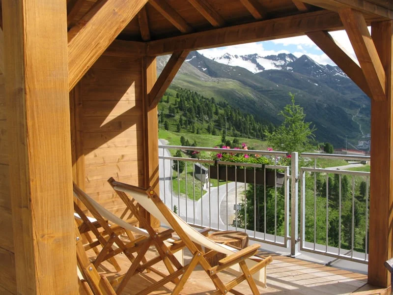 Balcony with wooden chairs overlooking snowy mountain peaks