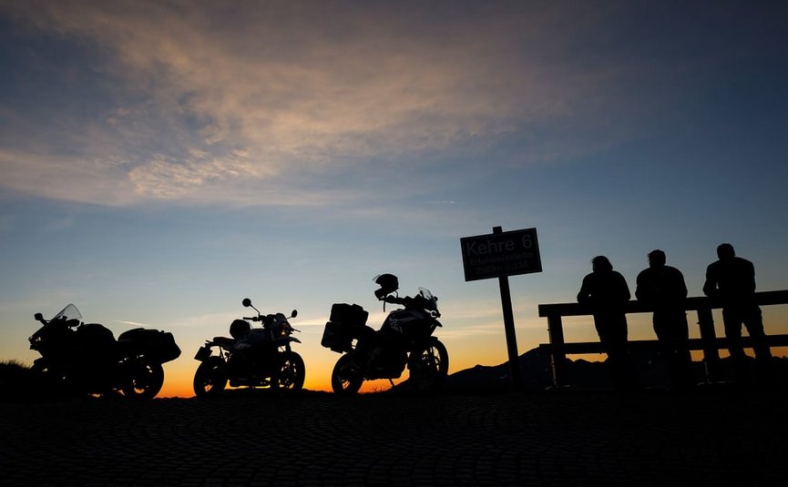 Silhouettes of motorcycles and people at sunset on a mountain road