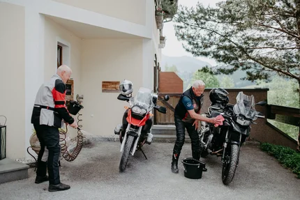 Steirerman Zwei ältere Männer reinigen ihre Motorräder vor einem Haus