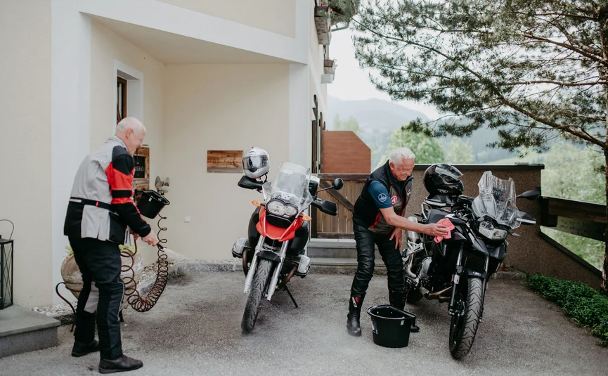 Steirerman Zwei ältere Männer reinigen ihre Motorräder vor einem Haus