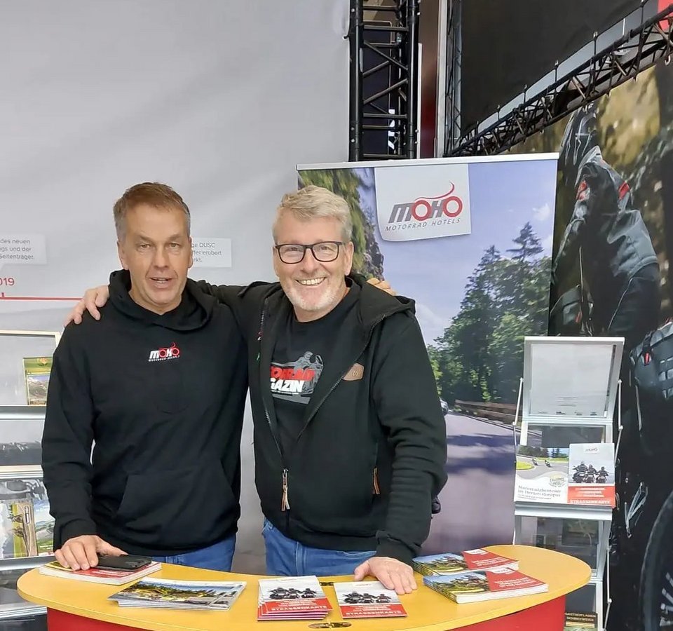 Zwei Männer an einem Messestand von MOHO Motorrad Hotels