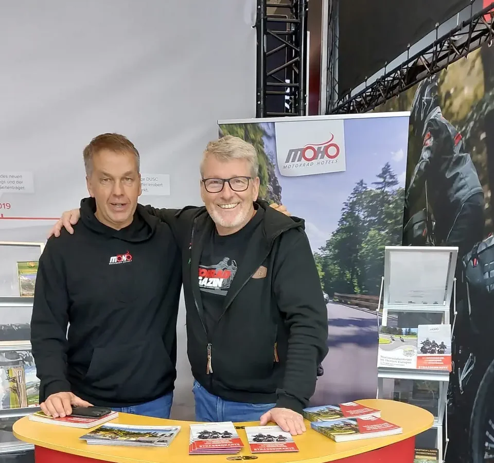 Twee mannen bij een MOHO Motorrad Hotels beursstand