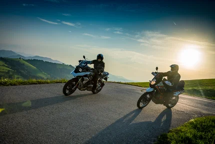 Twee motorrijders op een kronkelende bergweg bij zonsondergang