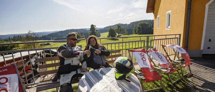 Motorcyclists enjoy sunny break with drinks on terrace overlooking mountains