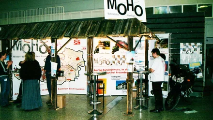 Geschichte der MoHo's Messestand mit MoHo Motorradhotels in den Alpen und Besuchern