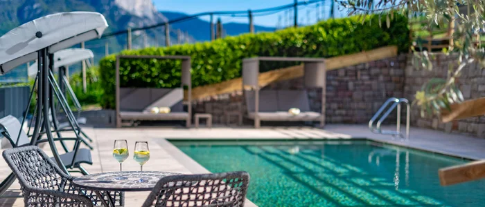 Pool terrace with two drinks on a table and mountain view in the background